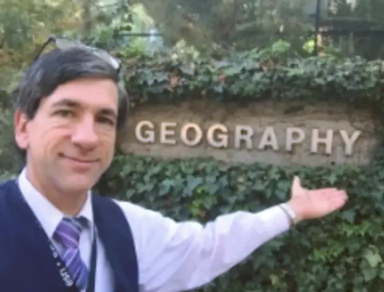 Renowned geographer Dr Joseph Kerski strikes a pose beside a Geography letter logo