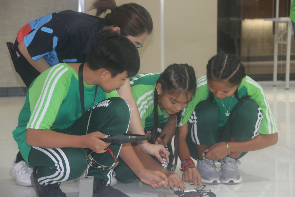 a female STEM teacher guiding her students how to operate a mini drone