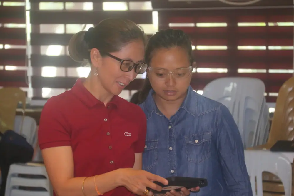 a drone instructor showing her trainee what's on the screen of the tablet she's holding