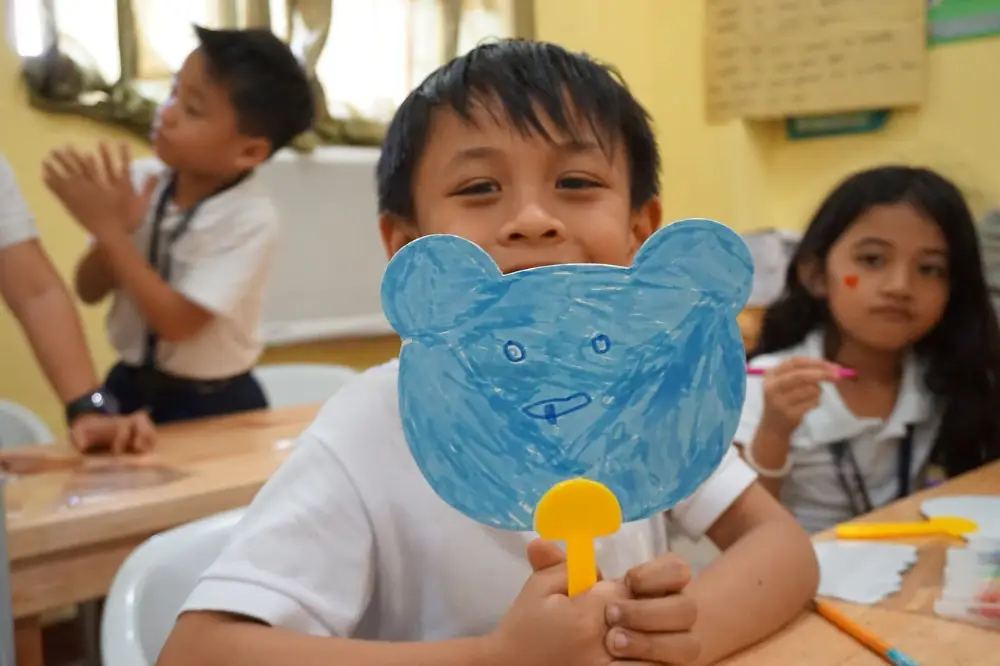 Filipino child holding a bear-head shaped fan