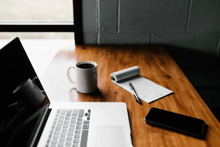 laptop, notepad, coffee and mobile phone laid on the table