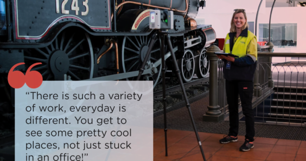 a female surveyor standing by a tripod and tram inside a museum