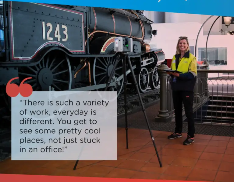 a female surveyor standing by a tripod and tram inside a museum