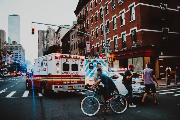 medical, police vehicles, and pedestrians passing through an intersection