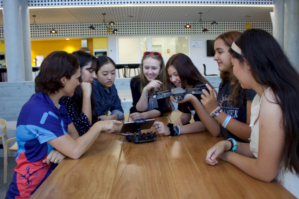 a group of young women being taught how to fly education drones in the school
