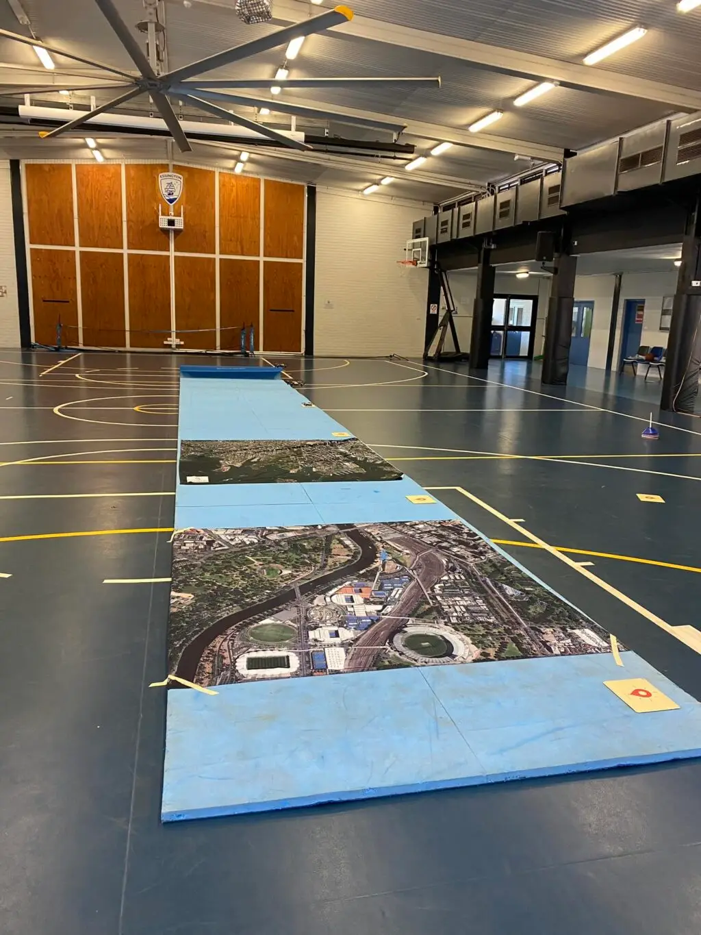 Indoor court with aerial map puzzle on floor.