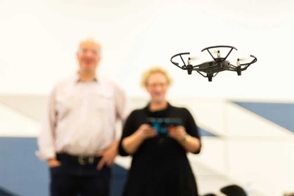Drone flying indoors with two people watching.