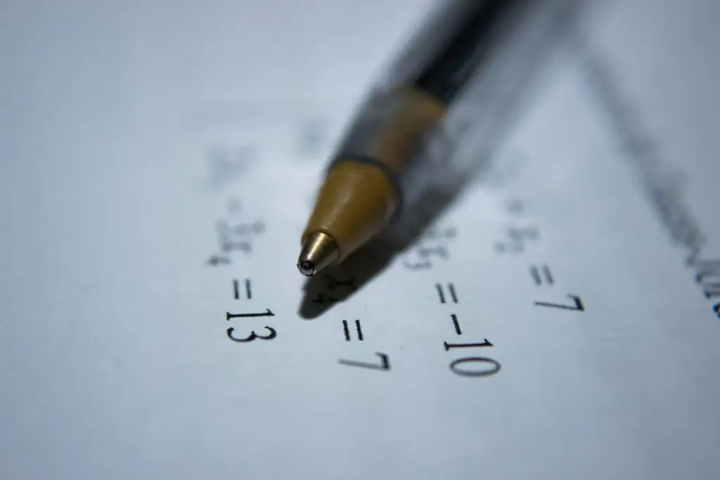 Pen on paper with math equations.