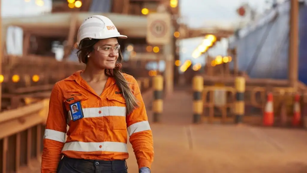 Female worker in safety gear at industrial site.