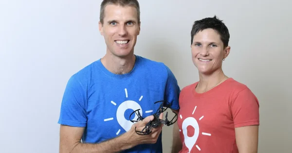 a man holding a small drone while standing next to his female colleague