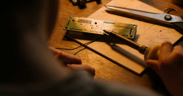 a man fixing a circuit board under an incandescent light source