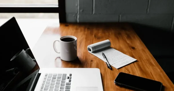 laptop, notepad, coffee and mobile phone laid on the table